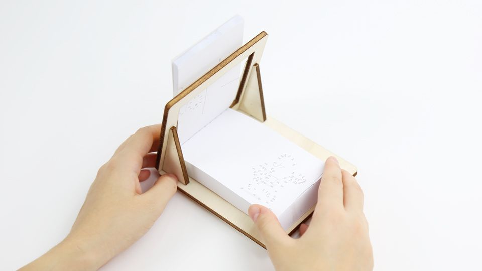 FLIPBOKU HOLDER - a practical tool that will enrich your experience with our interactive flip books Molecularis, Blanko and Dots &amp; Lines. It gives you some more freedom of movement while coloring, drawing, or connecting the dots.